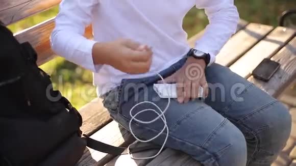 帅气的十几岁男孩从他的背包里拿了一个叫powerbark的东西来给smarphone充电秋天公园里的可爱男孩视频的预览图