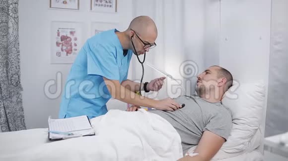 穿着制服的男医生检查躺在床上病房的病人视频的预览图