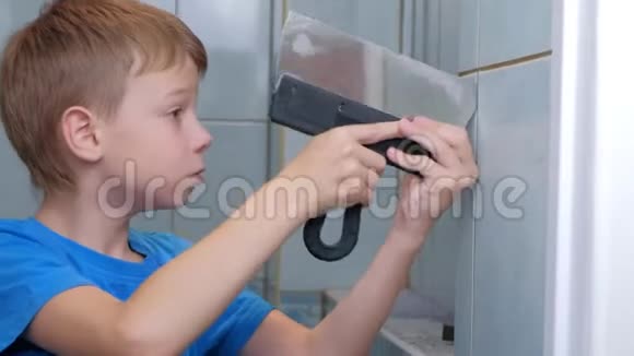 小男孩在家做翻新修理他从厕所的墙上移除瓷砖视频的预览图
