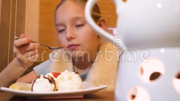 小女孩在咖啡馆吃冰淇淋的特写镜头视频的预览图