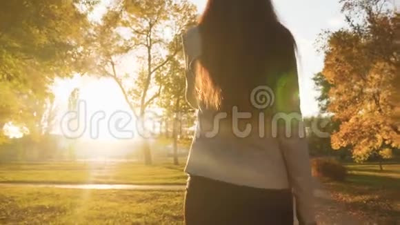 商务女性在打电话女人带着黑色公文包在夕阳下的公园里散步视频的预览图