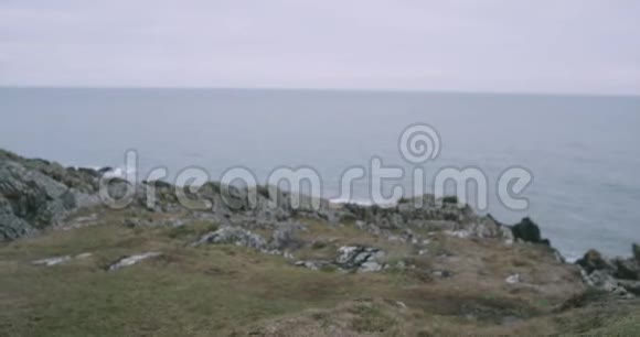 镜头前特写游客漫步到山岸欣赏山海景观视频的预览图