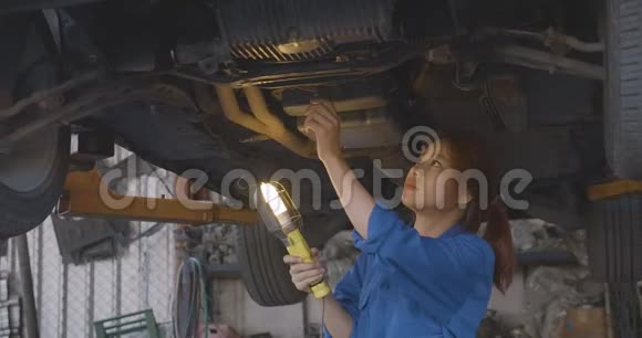 女汽车修理工在车库检查汽车起落架视频的预览图