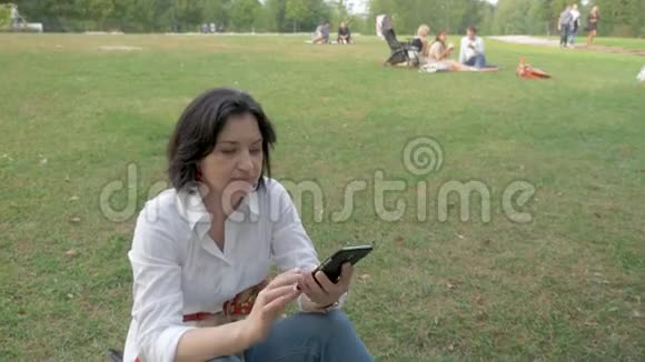 一个在空地上休息的女人的肖像并在她的手机上读取信息视频的预览图