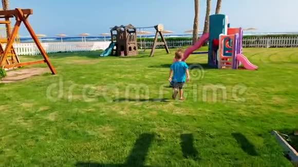 4k视频快乐的小男孩在公园的操场上跑步和打球视频的预览图