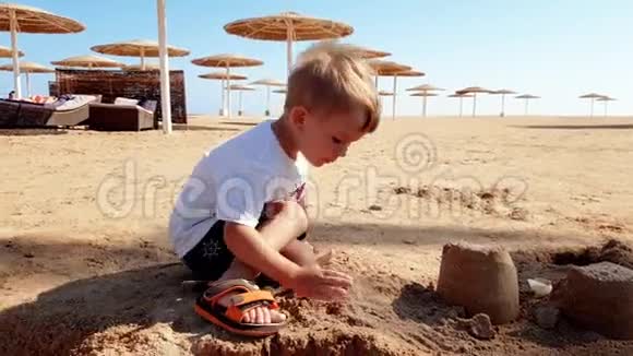小男孩在海边玩湿沙的4k镜头视频的预览图