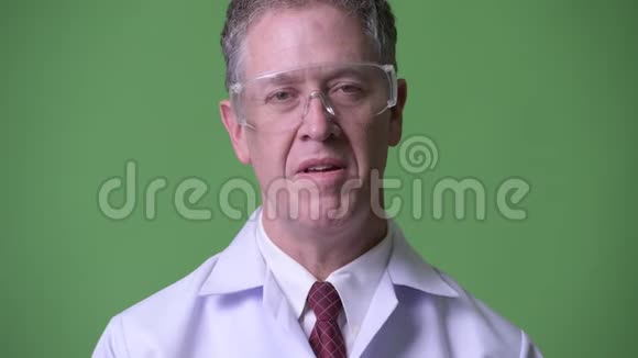 带防护眼镜的成熟男医生接受采访视频的预览图