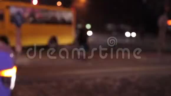 随着汽车红绿灯和建筑物的出现人们在夜晚穿过街道视频的预览图