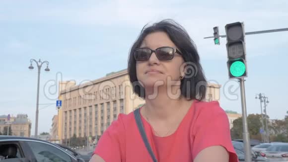 一位中年妇女在城市里休息的肖像在移动汽车的背景下特写视频的预览图