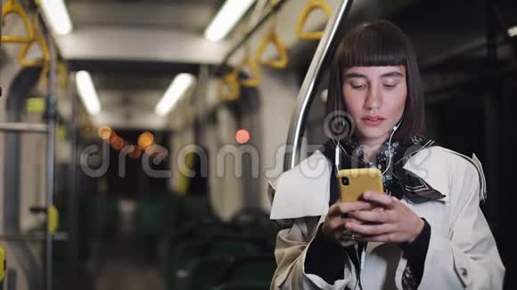 乘坐公共交通工具听音乐和浏览黄色耳机的美女画像视频的预览图