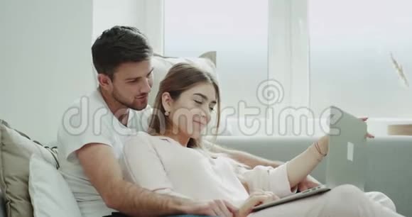 这对年轻夫妇的画像是用笔记本在沙发上订的两人都穿着睡衣视频的预览图