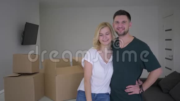 一对幸福夫妻的画像新房主在盒子的背景上展示公寓的钥匙和重新安置时的拥抱视频的预览图