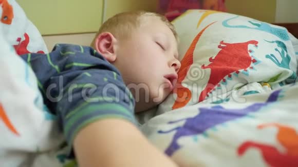这个男孩和恐龙睡在枕头上特写镜头视频的预览图