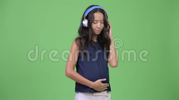 年轻的怀孕多民族女商人听音乐视频的预览图