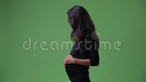 年轻美丽的怀孕多民族妇女摸着肚子抬头看着视频的预览图