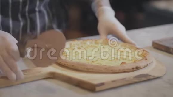 厨师手在手套切割热比萨饼基地通过滚动比萨饼切割机特写熟练的皮萨约罗在视频的预览图