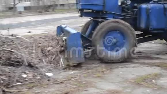 推土机小挖掘机在城市街道上移动干树枝和草视频的预览图