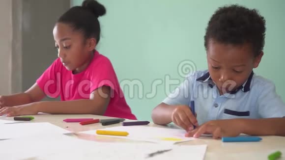 非裔美国儿童学习如何用蜡笔在桌子上画画视频的预览图