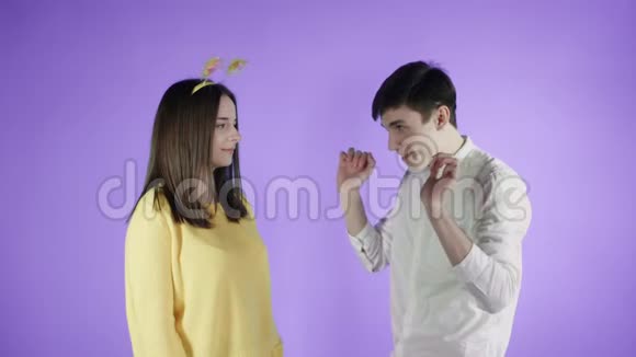 年轻的女人和男人在紫色的背景上用五颜六色的纸屑跳舞视频的预览图