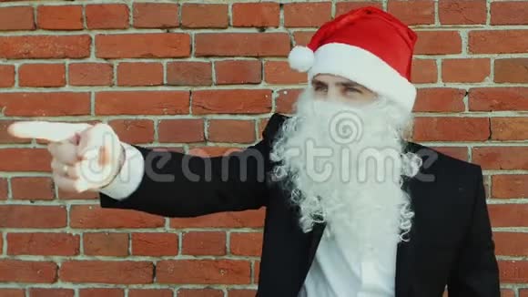 像圣诞老人这样的人用食指在镜头前挑选和展示圣诞快乐2019年新年红色视频的预览图