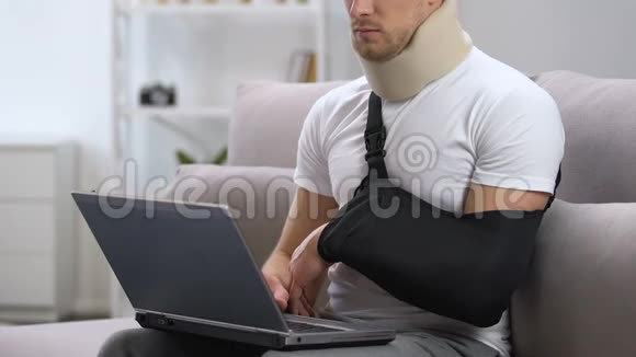 带手臂吊带和颈项圈的人在家中用笔记本电脑工作创伤治疗视频的预览图