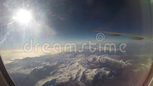 透过飞机窗户观看雪山上空的飞机机翼视频的预览图