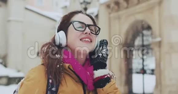 一幅可爱的笑脸女孩被遗弃在雪地里的特写肖像她用无线听音乐视频的预览图