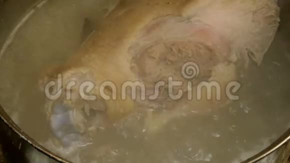 骨头上的猪肉腿上的关节是在金属蒸煮锅中煮沸的肉汤中煮熟的视频的预览图