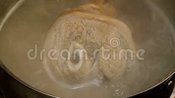 骨头上的猪肉腿上的关节是在金属蒸煮锅中煮沸的肉汤中煮熟的视频的预览图