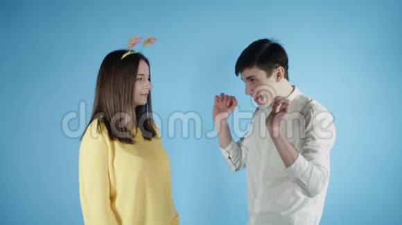 年轻的女人和男人在蓝色背景上用五颜六色的纸屑跳舞视频的预览图