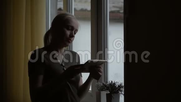 站在窗前一个女人拿着一张画框看着她抚摸着他的手视频的预览图
