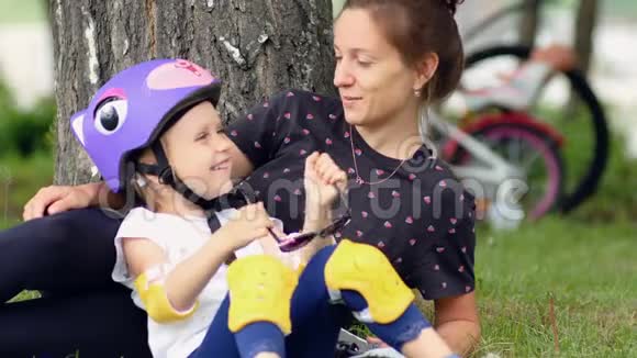 妈妈和女儿骑自行车后在公园里休息视频的预览图