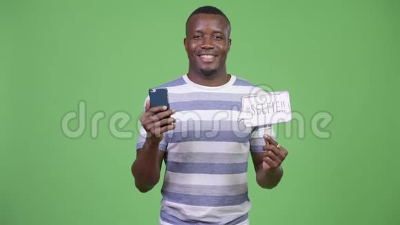 年轻快乐的非洲男人展示手机和自拍纸标志视频的预览图