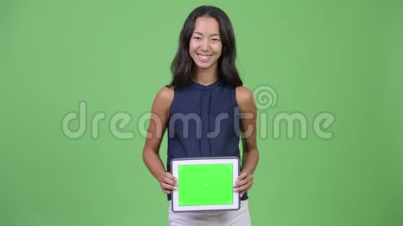 年轻快乐怀孕多民族的女商人肚子上放着数码平板电脑视频的预览图