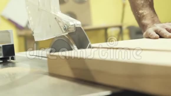 在车间或工厂里用圆锯和切割大木板的工人的手视频的预览图