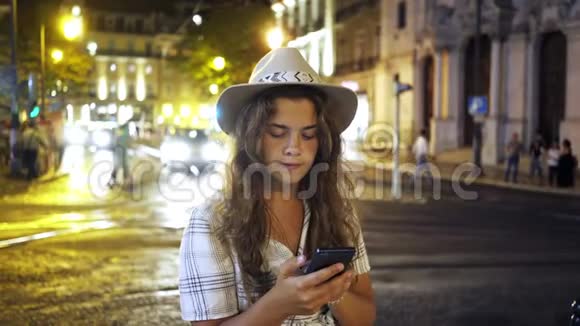 晚上在街上使用智能手机的年轻女子视频的预览图