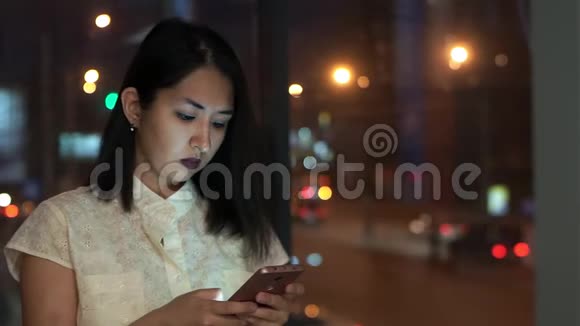 女孩在办公室里翻转智能手机的屏幕对着夜城视频的预览图