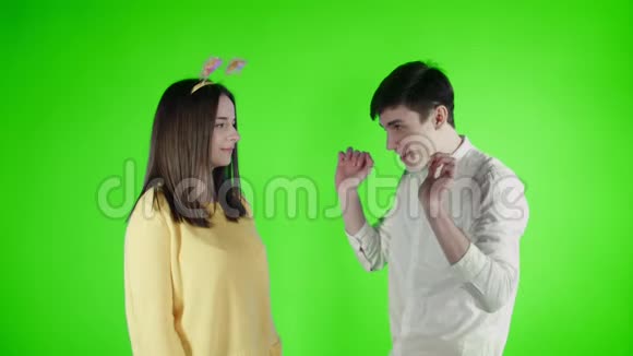 年轻的女人和男人正在绿色的屏幕上用五颜六色的纸屑跳舞视频的预览图