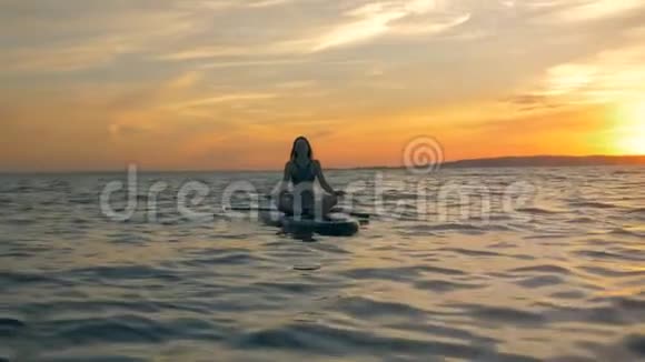 在海里休息的女人女运动员骑完一圈后就在冲浪板上冥想视频的预览图