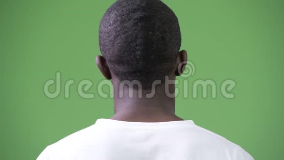 绿色背景下脖子疼痛的非洲年轻人的后视图视频的预览图