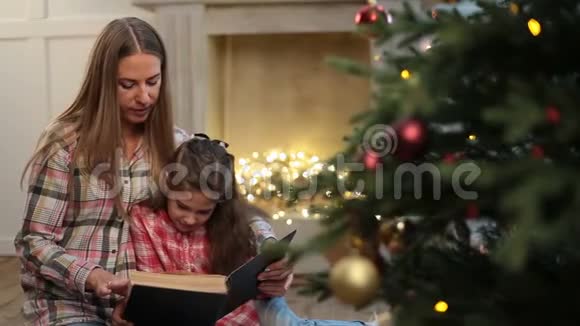 妈妈在圣诞树附近给女儿读书视频的预览图