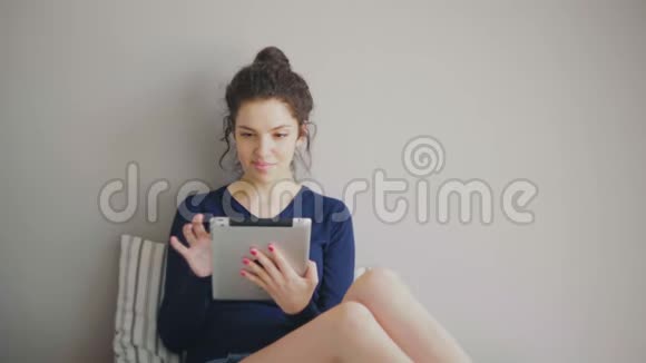 可爱漂亮的女孩在家里用平板电脑视频的预览图