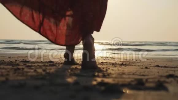 美丽的女天使在日落时赤脚走向大海的剪影视频的预览图