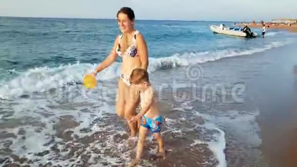 4k镜头欢快的幼儿男孩手牵着妈妈在沙滩上散步视频的预览图