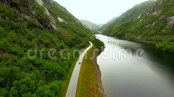 空中观景这辆车沿着河在群山之间的公路上行驶挪威视频的预览图