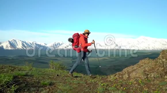 那个背着红色背包的旅行者站在山边望着雪山慢镜头视频的预览图