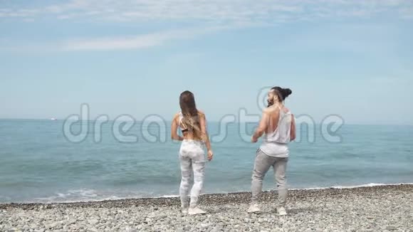 年轻的健身夫妇站在海滩上望着地平线视频的预览图