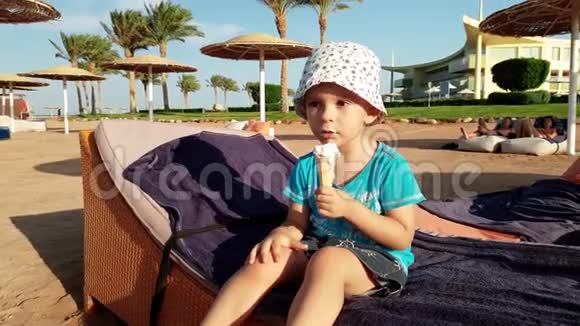 4k片幼儿男孩拿着冰淇淋坐在沙滩上视频的预览图