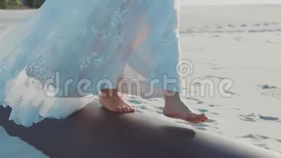 赤着脚的女孩优雅地慢慢地沿着沙中的管子走着一位优雅的年轻女士戴着一个长长的婚礼视频的预览图