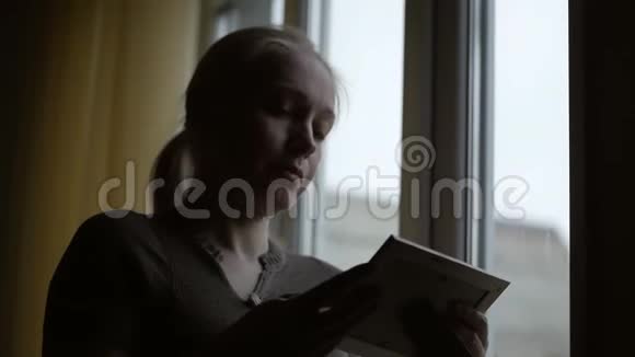 站在窗前一个女人拿着一张画框看着她抚摸着他的手视频的预览图